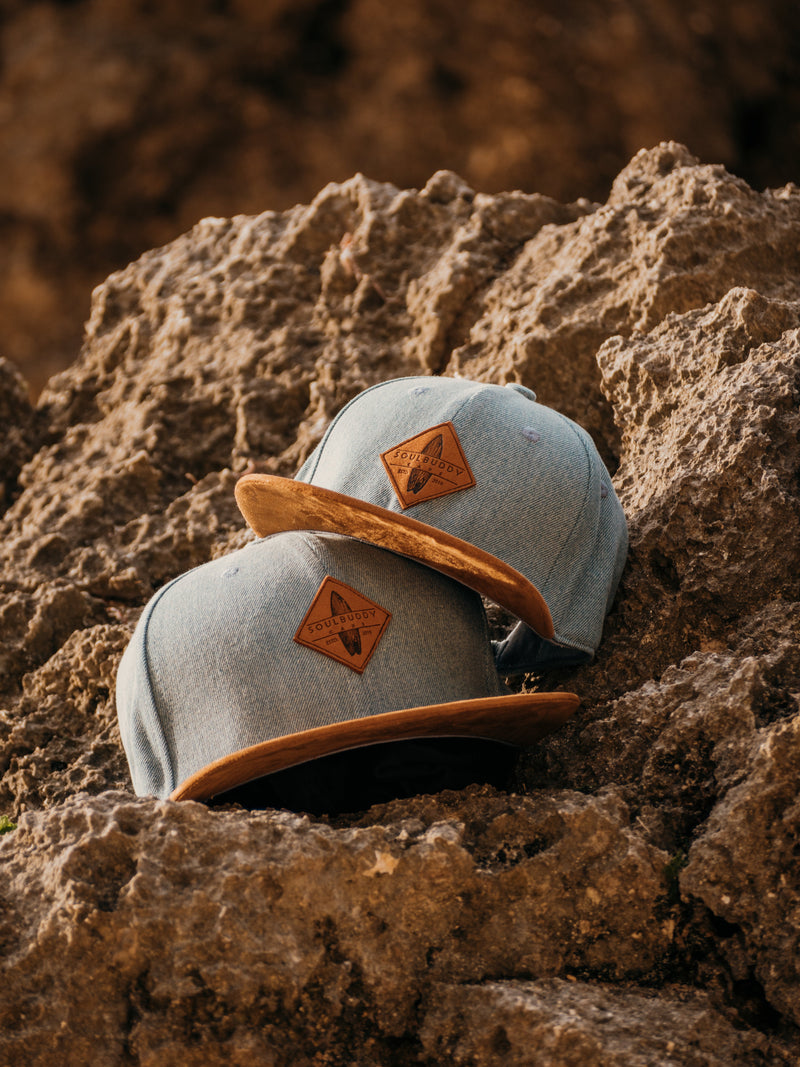 Zwei Soulbuddy Snapback Caps in Jeansblau mit Wildleder-Schirm auf einem Felsen – welche Formen von Caps gibt es