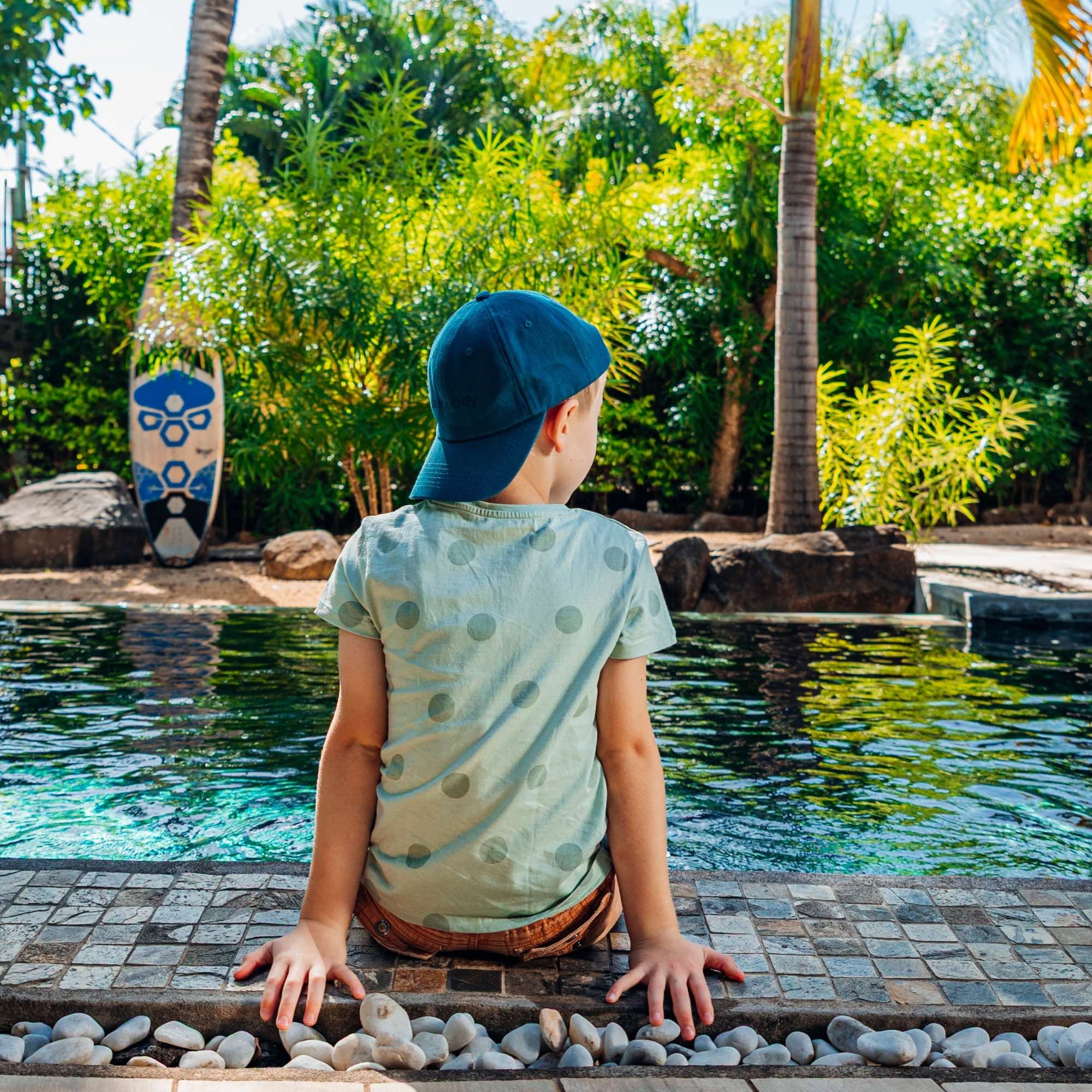 Junge mit petrolfabener Dad Hat Cap am Pool