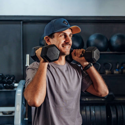 Soulbuddy Performance Cap für Damen und Herren – sportlicher Mann mit blauer Cap beim Krafttraining mit Kurzhanteln