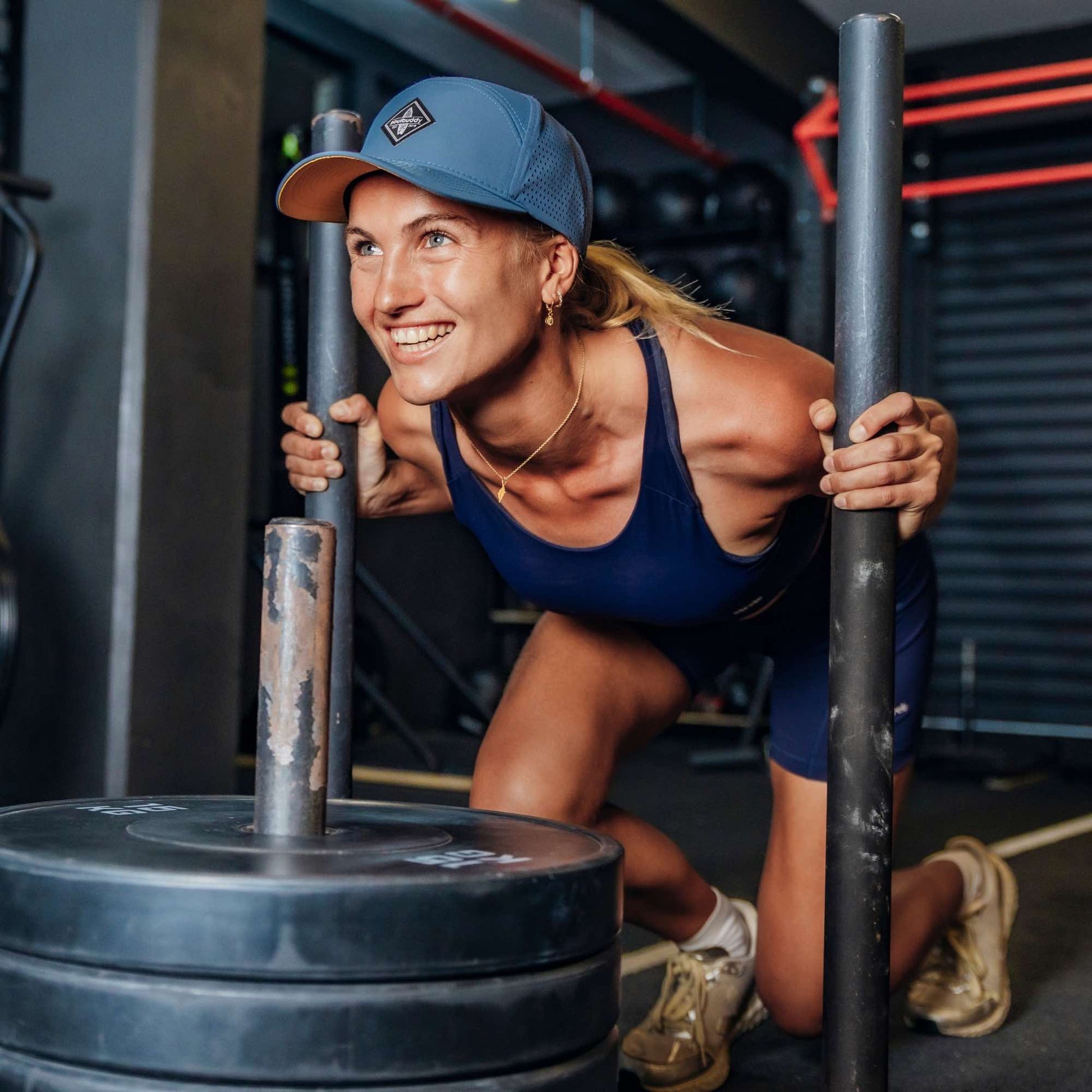 Sportliche Frau trägt blaue Performance Snapback Cap beim intensiven Workout im Fitnessstudio