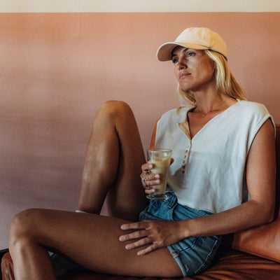 Soulbuddy Partnerlook Dad Hat Basecaps 2er-Set für Eltern und Kind in Cream – Frau mit Eiskaffee vor rosa Wand