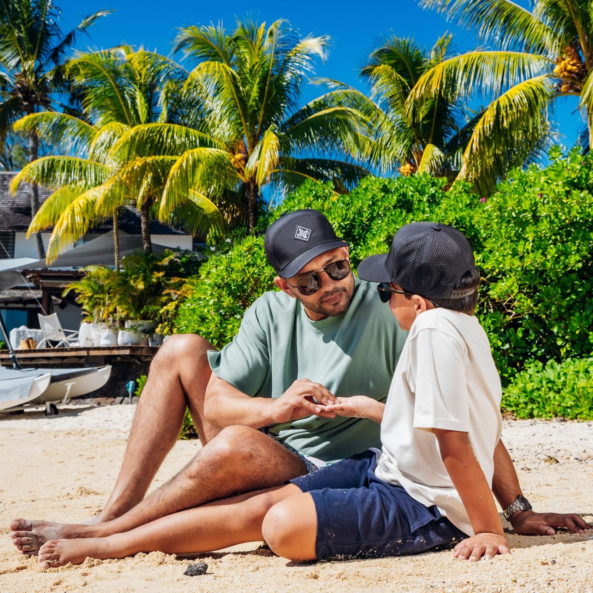 Vater und Sohn tragen schwarze Caps am Strand