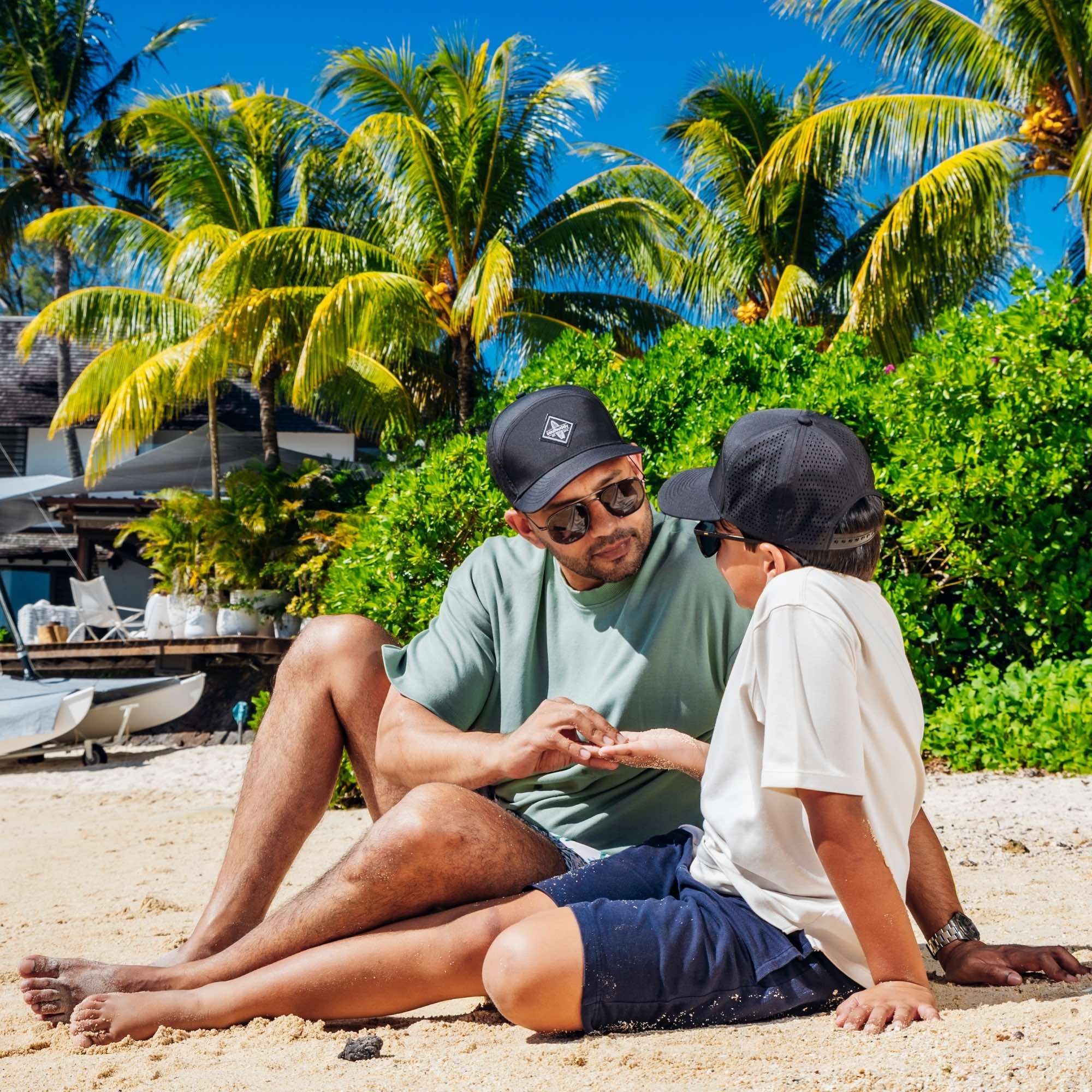 Vater und Sohn tragen schwarze Caps am Strand