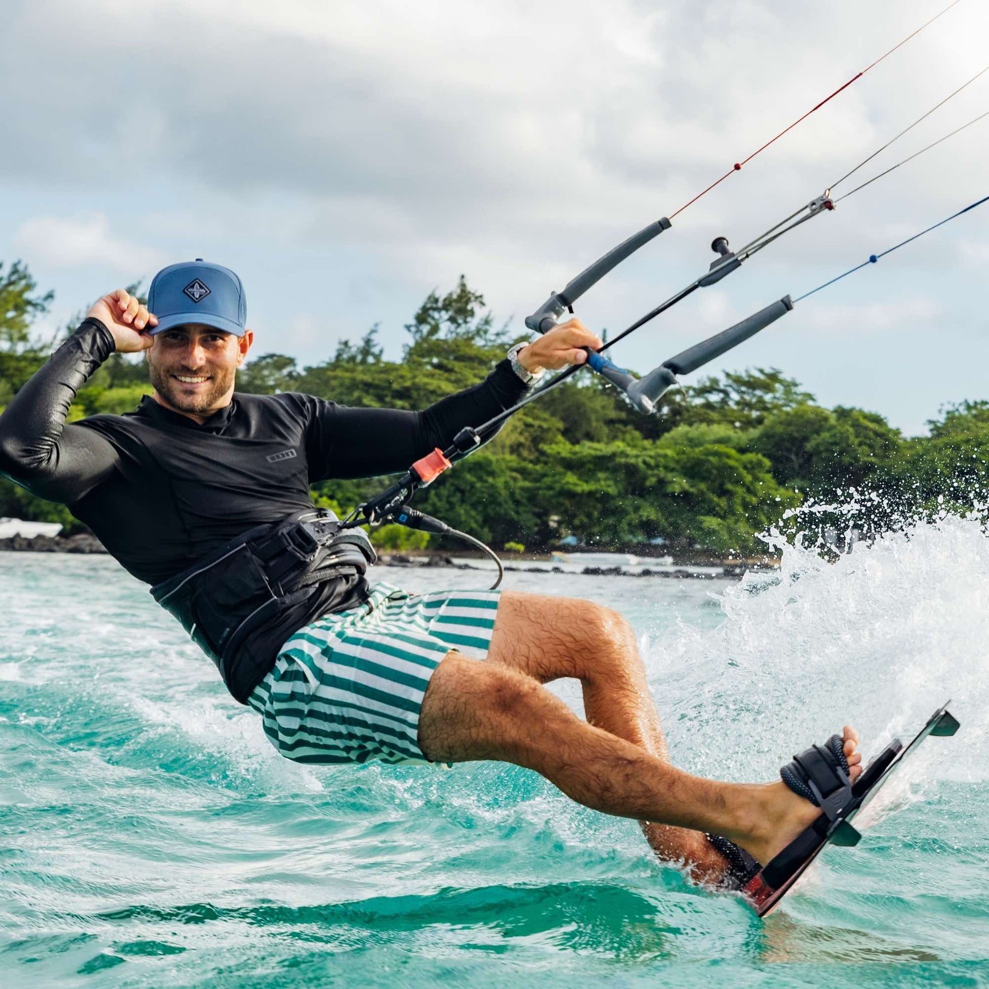 Sportlicher Mann trägt blaue Performance Snapback Cap beim Kitesurfen auf dem Meer bei dynamischen Bedingungen